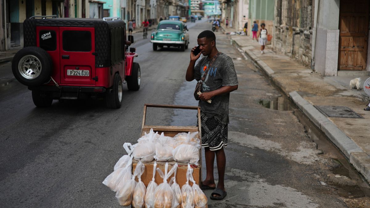 A bread vendor holds a cell phone up to his ear during irregular connectivity due to a blackout in Havana, Tuesday, March 17, 2026. (AP Photo/Ramon Espinosa)