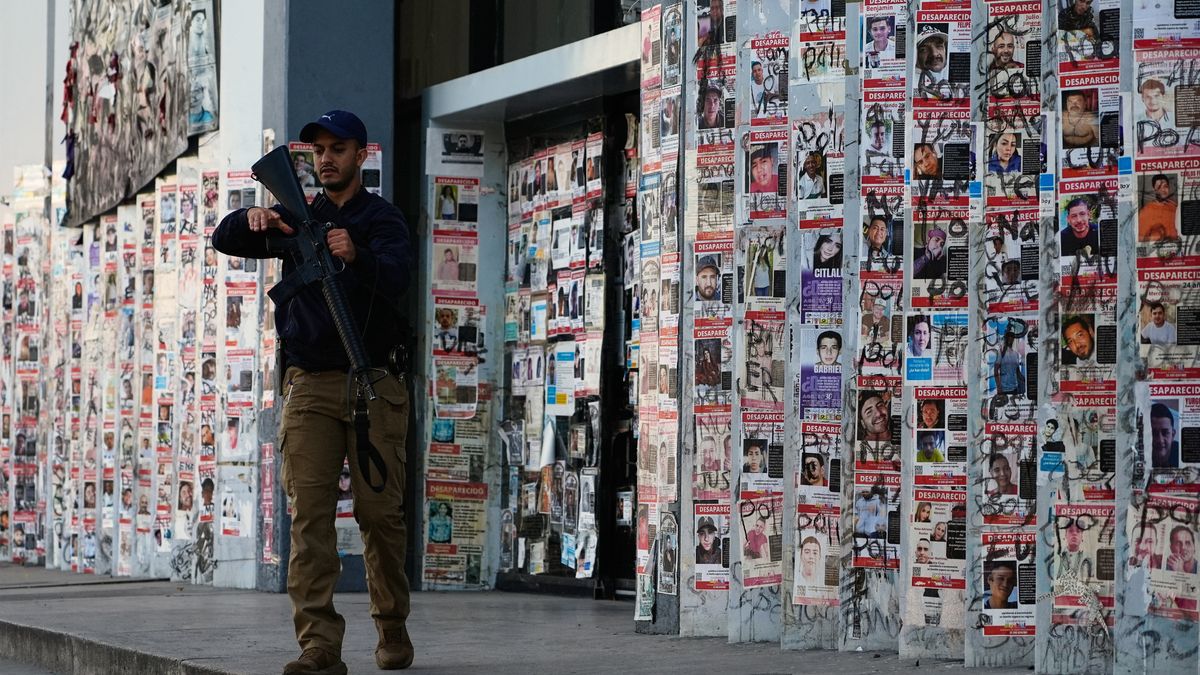 A police officer walks past posters of missing persons in front of the Special Prosecutor's Office for Missing Persons in Guadalajara, Mexico, Wednesday, Feb. 25, 2026. (AP Photo/Marco Ugarte)