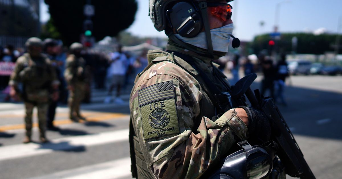 FILE - An ICE Special Response Team member stands guard outside the Metropolitan Detention Center, while protesters gather