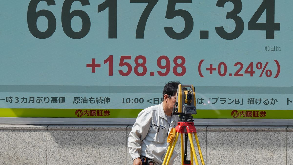 A surveyor works in front of a stock market chart Monday, Aug. 24, 2026 in Tokyo. (AP Photo/Eugene Hoshiko)