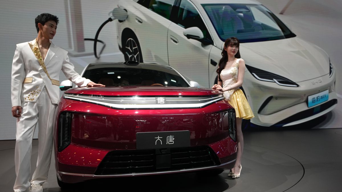 FILE - Models stand next to a latest EV car from Chinese automaker BYD showcased at the Auto China 2026, in Beijing, April 25, 2026. (AP Photo/Andy Wong, File)