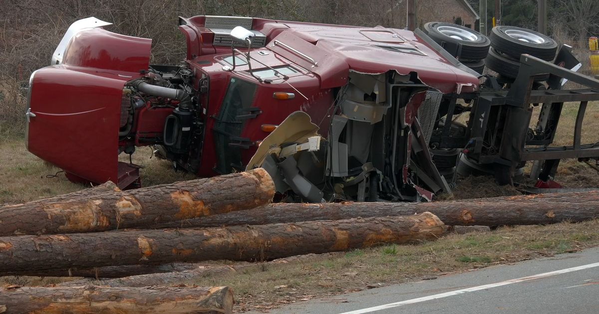 Log truck overturns on U.S. 70W