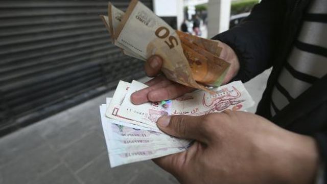 A man holds Algerian and European, top, bank notes Friday, Feb. 9, 2024 in Algiers. In Algeria, people have long relied on foreign currencies to buy imported items in short supply or finance their children's educations abroad. But the value of the Algerian dinar has recently swung wildly on the country's black market as its value has plummeted compared to euros, pounds and dollars. The oil-rich country's large black market for foreign currency is among the signs of its economic woes. (AP Photo/Anis Belghoul) A man holds Algerian and European, top, bank notes Friday, Feb. 9, 2024 in Algiers. In Algeria, people have long relied on foreign currencies to buy imported items in short supply or finance their children's educations abroad. But the value of the Algerian dinar has recently swung wildly on the country's black market as its value has plummeted compared to euros, pounds and dollars. The oil-rich country's large black market for foreign currency is among the signs of its economic woes. (AP Photo/Anis Belghoul)