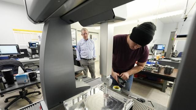 As Reata Engineering and Machine Works CEO Grady Cope looks on, a worker prepares a Hexagon machine to confirm that parts meet customers' standards, Thursday, Feb. 15, 2024, in Englewood, Colo. At Reata, which makes parts for aircraft and medical device manufacturers, "efficiency was kind of forced on us,'' Cope said. (AP Photo/David Zalubowski) As Reata Engineering and Machine Works CEO Grady Cope looks on, a worker prepares a Hexagon machine to confirm that parts meet customers' standards, Thursday, Feb. 15, 2024, in Englewood, Colo. At Reata, which makes parts for aircraft and medical device manufacturers, "efficiency was kind of forced on us,'' Cope said. (AP Photo/David Zalubowski)