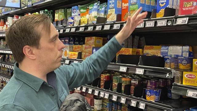 Stuart Dryden reaches for an item at a grocery store on Wednesday, Feb. 21, 2024, in Arlington, Va. Dryden is aware of big price disparities between branded products and their store-label competitors, which he now favors. (AP Photo/Chris Rugaber) Stuart Dryden reaches for an item at a grocery store on Wednesday, Feb. 21, 2024, in Arlington, Va. Dryden is aware of big price disparities between branded products and their store-label competitors, which he now favors. (AP Photo/Chris Rugaber)