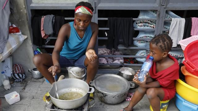 A woman cooks at shelter for families displaced by gang violence, in Port-au-Prince, Haiti, Friday, March 8, 2024. The violence as anti-government gangs battle police in the streets has crippled Haiti’s economy and made it extremely difficult for many of the country's most vulnerable to feed themselves.(AP Photo/Odelyn Joseph) A woman cooks at shelter for families displaced by gang violence, in Port-au-Prince, Haiti, Friday, March 8, 2024. The violence as anti-government gangs battle police in the streets has crippled Haiti’s economy and made it extremely difficult for many of the country's most vulnerable to feed themselves.(AP Photo/Odelyn Joseph)