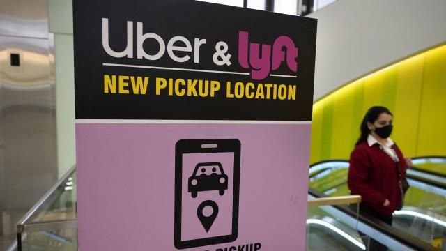 FILE - In this Feb. 9, 2021 file photo, a passer-by walks past a sign offering directions to an Uber and Lyft ride pickup location at Logan International Airport, in Boston. Lyft and Uber are threatening to halt operations in Minneapolis because of a city ordinance to increase wages for app-based drivers, the latest back-and-forth that underscores a longtime fight between gig economy workers and the tech giants.(AP Photo/Steven Senne, File) FILE - In this Feb. 9, 2021 file photo, a passer-by walks past a sign offering directions to an Uber and Lyft ride pickup location at Logan International Airport, in Boston. Lyft and Uber are threatening to halt operations in Minneapolis because of a city ordinance to increase wages for app-based drivers, the latest back-and-forth that underscores a longtime fight between gig economy workers and the tech giants.(AP Photo/Steven Senne, File)