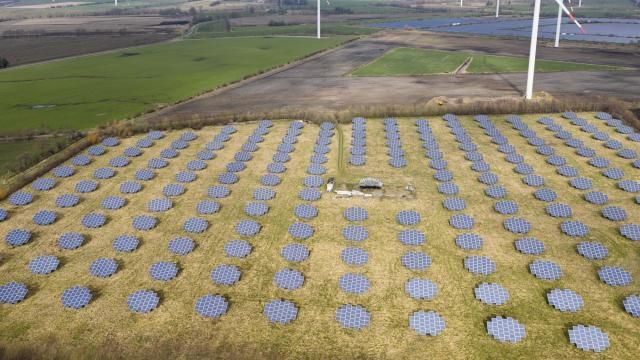 Solar panels stand on the edge of a wind farm in Sprakebuell, Germany, Thursday, March 14, 2024. Sprakebuell is something of a model village for the energy transition - with an above-average number of electric cars, a community wind farm and renewable heat from biogas. All houses in the village center have been connected to the local heating network and all old oil heating systems have been removed. Aerial photography with a drone. (AP Photo/Frank Molter) (AP Photo/Frank Molter) Solar panels stand on the edge of a wind farm in Sprakebuell, Germany, Thursday, March 14, 2024. Sprakebuell is something of a model village for the energy transition - with an above-average number of electric cars, a community wind farm and renewable heat from biogas. All houses in the village center have been connected to the local heating network and all old oil heating systems have been removed. Aerial photography with a drone. (AP Photo/Frank Molter) (AP Photo/Frank Molter)