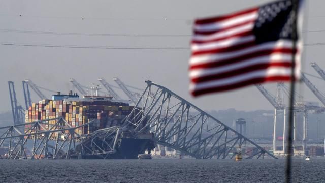 FILE - A U.S. flag flies on a moored boat as the container ship Dali rests against the wreckage of the Francis Scott Key Bridge, Tuesday, March 26, 2024, as seen from Pasadena, Md. (AP Photo/Mark Schiefelbein, File) FILE - A U.S. flag flies on a moored boat as the container ship Dali rests against the wreckage of the Francis Scott Key Bridge, Tuesday, March 26, 2024, as seen from Pasadena, Md. (AP Photo/Mark Schiefelbein, File)