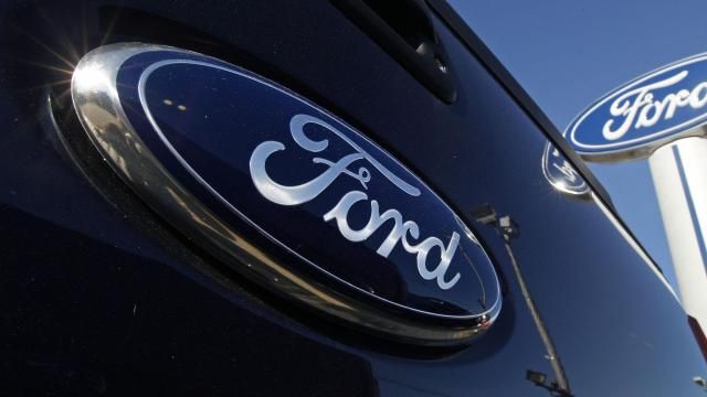 FILE - A Ford logo is on the tailgate of a pick-up truck and on a Ford dealership sign in Salem, N.H. (AP Photo/Charles Krupa, File)