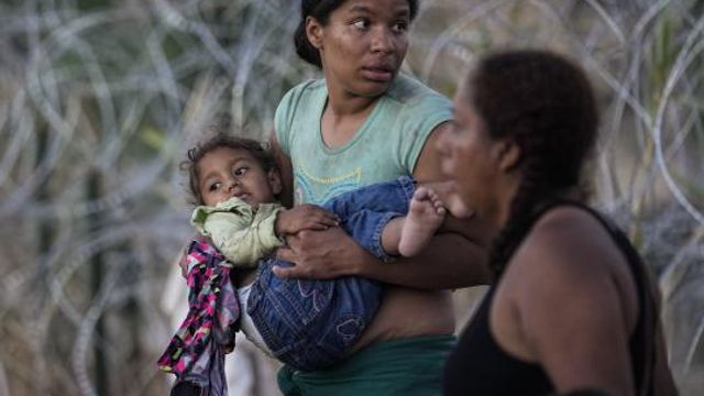 A woman carries her child after she and other migrants crossed the Rio Grande and entered the U.S. from Mexico, to be processed by U.S. Customs and Border Protection, Saturday, Sept. 23, 2023, in Eagle Pass, Texas. The image was part of a series by Associated Press photographers Ivan Valencia, Eduardo Verdugo, Felix Marquez, Marco Ugarte Fernando Llano, Eric Gay, Gregory Bull and Christian Chavez that won the 2024 Pulitzer Prize for feature photography. (AP Photo/Eric Gay) A woman carries her child after she and other migrants crossed the Rio Grande and entered the U.S. from Mexico, to be processed by U.S. Customs and Border Protection, Saturday, Sept. 23, 2023, in Eagle Pass, Texas. The image was part of a series by Associated Press photographers Ivan Valencia, Eduardo Verdugo, Felix Marquez, Marco Ugarte Fernando Llano, Eric Gay, Gregory Bull and Christian Chavez that won the 2024 Pulitzer Prize for feature photography. (AP Photo/Eric Gay)