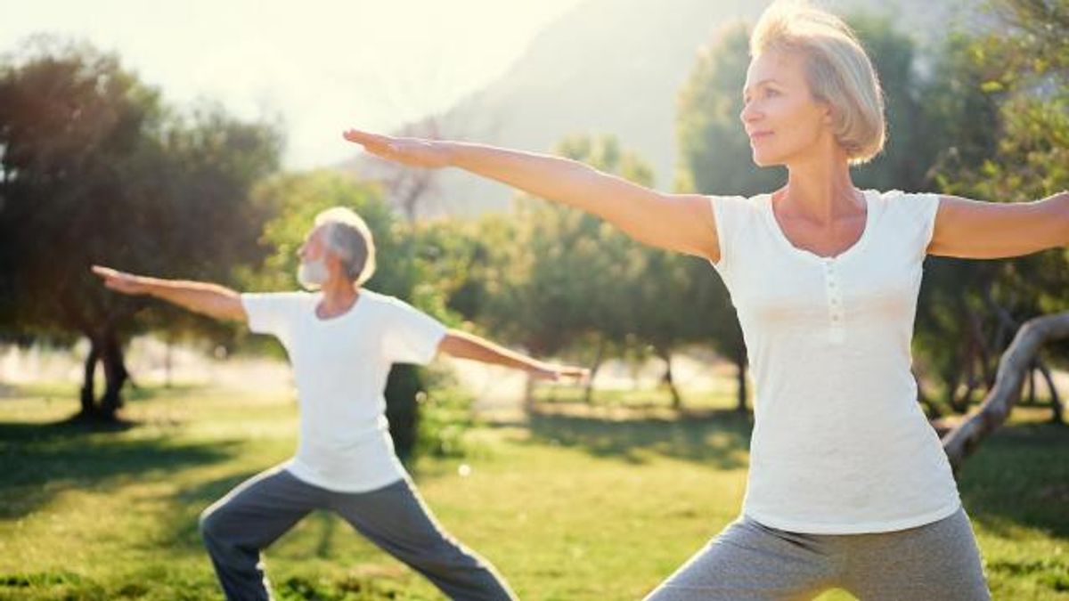 Yoga at park. Senior family couple exercising outdoors. Concept of healthy lifestyle.