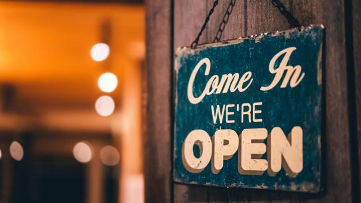 Open sign broad hanging on wood door front of cafe.
