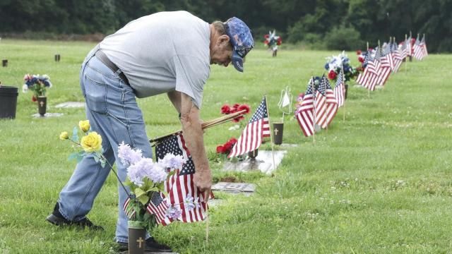 Retired Navy veteran Randy Melton places American flags at the gravesites of veterans in the Field of Honor on Tuesday in preparation for the Memorial Day weekend at Owensboro Memorial Gardens in Owensboro, Ky., on May 20, 2025. Melton is a member of all of the veterans organizations in town and volunteers every year to place the flags. (Alan Warren/The Messenger-Inquirer via AP)