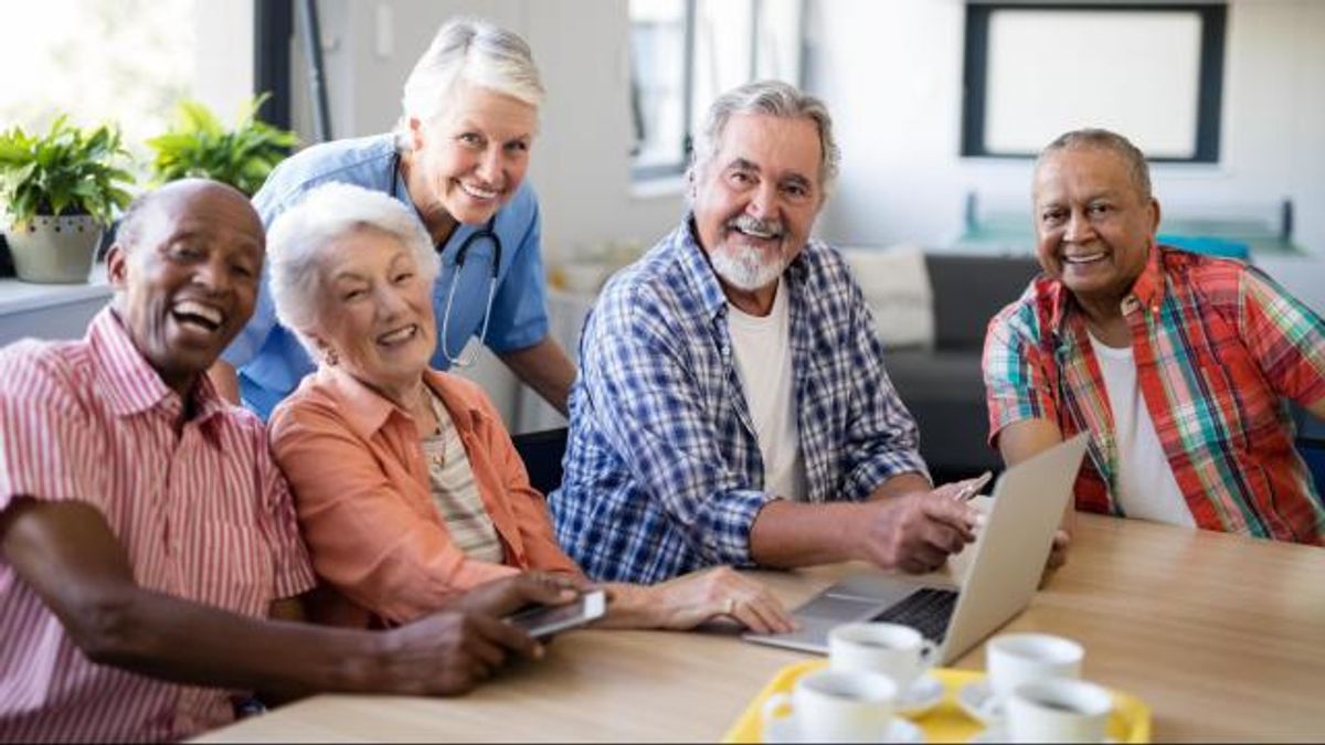 Portrait of smiling practitioner with senior people by table at 