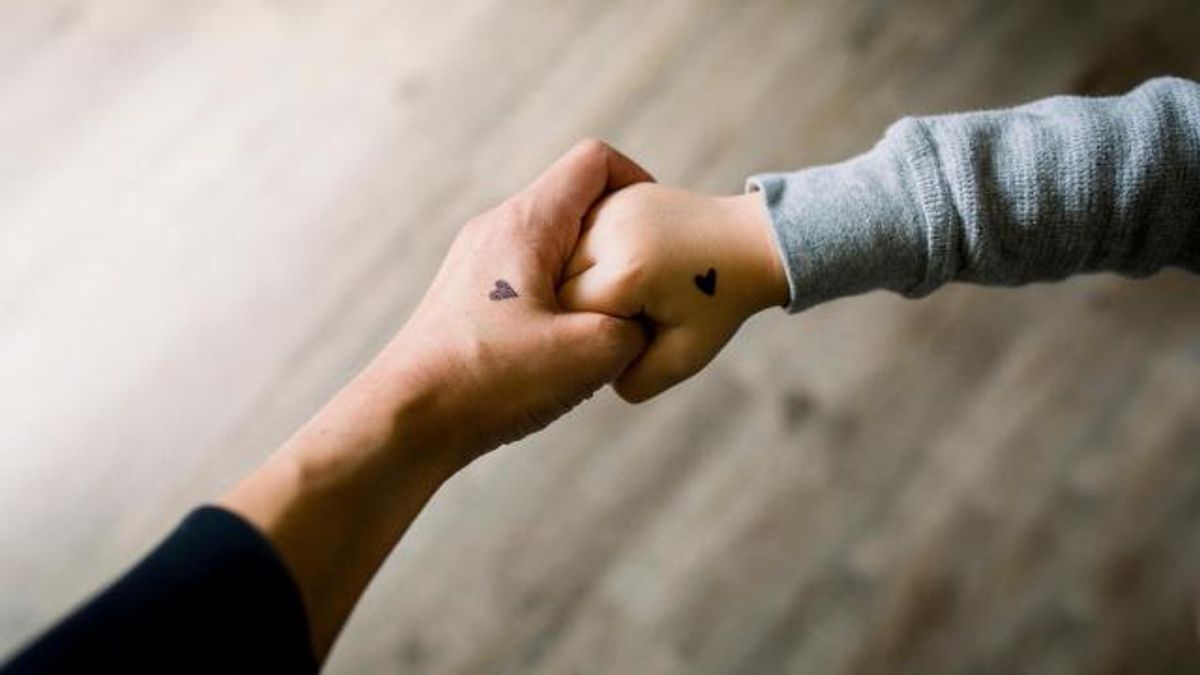 Parent and child holding hands with hearts