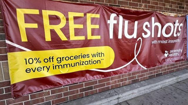 FILE - A sign for flu vaccination is displayed outside of a grocery store in Glenview, Ill., Thursday, Feb. 15, 2024. On Friday, April 26, 2024, the Centers for Disease Control and Prevention said last week, for the third straight week, medical visits for flu-like illnesses dipped below the threshold for what's counted as an active flu season. (AP Photo/Nam Y. Huh)