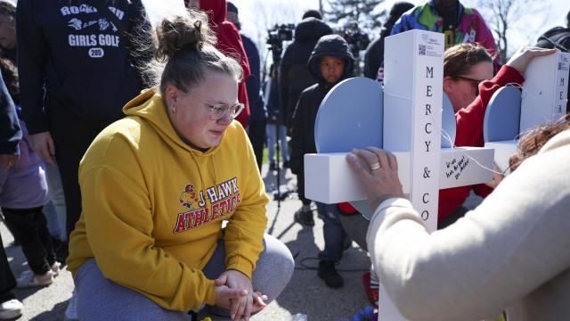 Delanie Palmer, friend of Jenna Newcomb, crouches near a cross for Newcomb during a vigil Thursday, March 28, 2024, for the victims of Wednesday's stabbings in Rockford, Ill (Eileen T. Meslar/Chicago Tribune via AP)