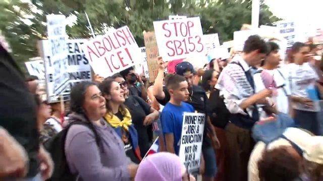 People gather in downtown Raleigh's Moore Square to protest President Trump's immigration policies