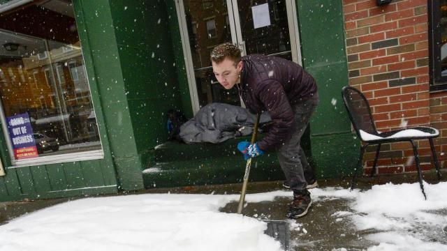 Mikey Reynolds, an employee at The Works on Main Street in Brattleboro, Vt., shovels the sidewalk in front of the restaurant as a person who is facing homelessness sleeps in a door entryway while seeking refuge from the snow storm on Saturday, March 23, 2024. New England is battling a mix of wind, rain, sleet and heavy snow across the region Saturday with more than a foot of snow expected in ski county, but mostly rain, wind and possible flooding in southern areas and along the coast. (Kristopher Radder /The Brattleboro Reformer via AP) Mikey Reynolds, an employee at The Works on Main Street in Brattleboro, Vt., shovels the sidewalk in front of the restaurant as a person who is facing homelessness sleeps in a door entryway while seeking refuge from the snow storm on Saturday, March 23, 2024. New England is battling a mix of wind, rain, sleet and heavy snow across the region Saturday with more than a foot of snow expected in ski county, but mostly rain, wind and possible flooding in southern areas and along the coast. (Kristopher Radder /The Brattleboro Reformer via AP)