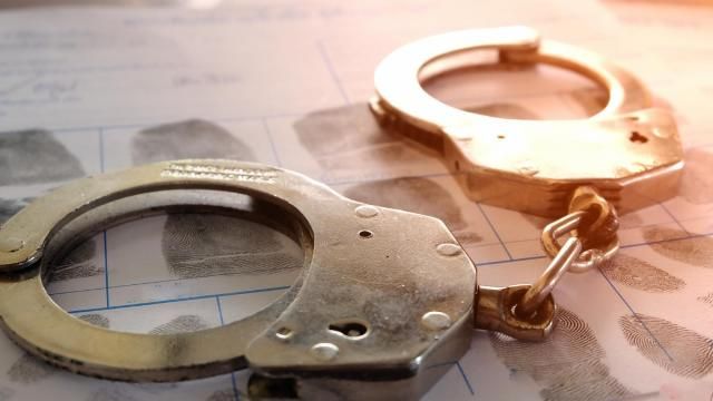 Handcuffs resting on a paper filled with fingerprint. Handcuffs resting on a paper filled with fingerprint.