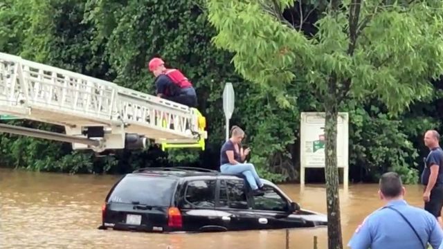 Floodwaters trap woman on top of SUV