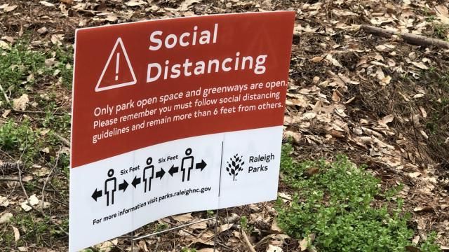 Signs at greenways ask people to social distance