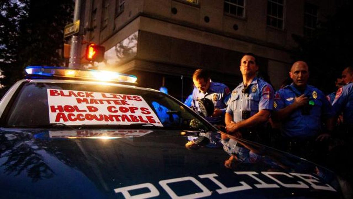 Raleigh police officers surround a police car while protests hover around them. One protester placed a sign on the car that reads: "Black Lives Matter, Hold Cops Accountable."
