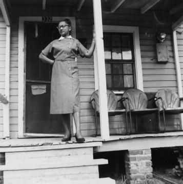 A woman named Jeanette Brown Adams Ferguson poses on the porch of her house on South Street in 1957. She worked at the Sandwich Shop on Wilmington Street for 22 years. Courtesy of the State Archives of North Carolina.