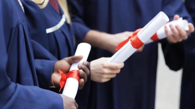 Generic photo of several students holding diplomas during graduation ceremony. 
