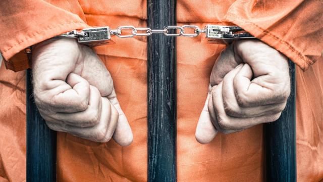 A man in an orange jumpsuit is locked in handcuffs in permission A man in an orange jumpsuit is locked in handcuffs in permission