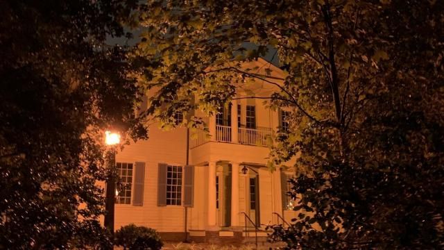 Mordecai House balcony peaking out from behind ancient oaks.