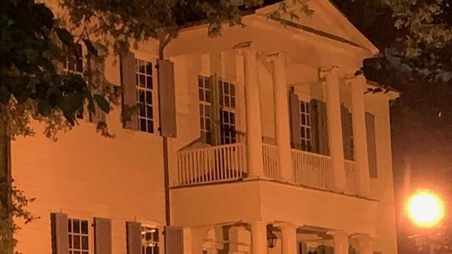 Mordecai House balcony peaking out from behind ancient oaks.