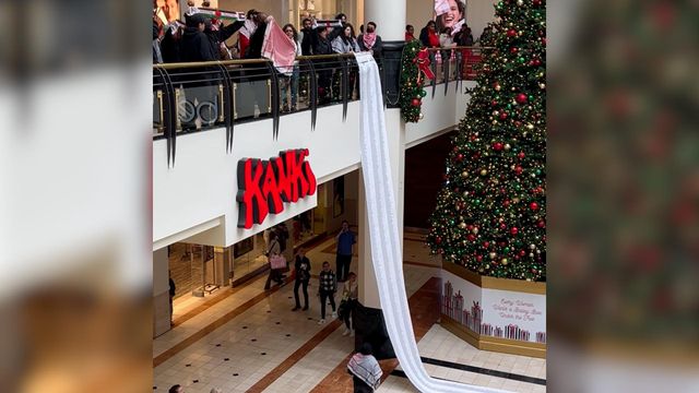 Pro-Palestinian protesters inside Crabtree Valley Mall drop scroll from second floor to first floor