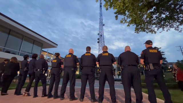 Raleigh police officers gathered outside WRAL News as the tower was lit blue.
