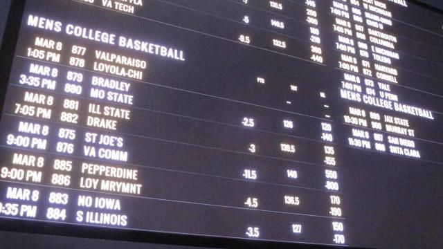 A sports wagering board shows college basketball games.