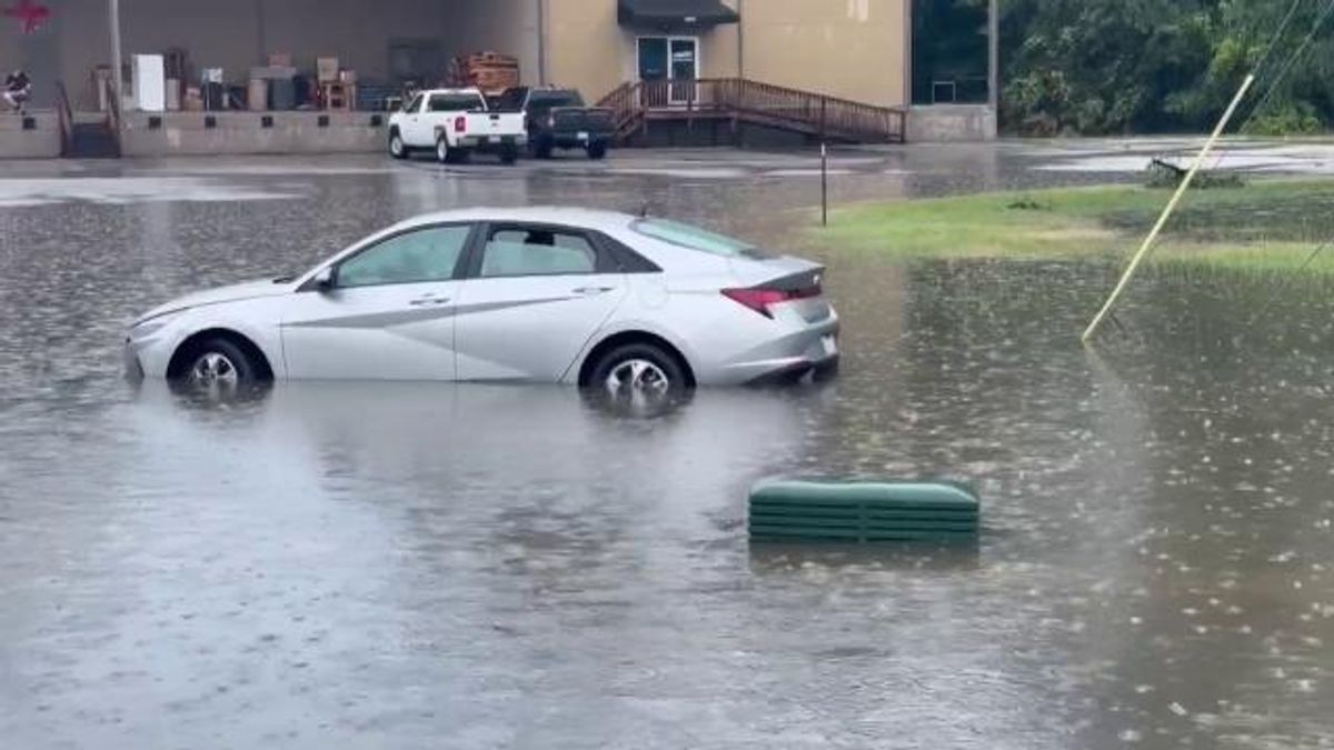 Man helps woman out of vehicle during flooding