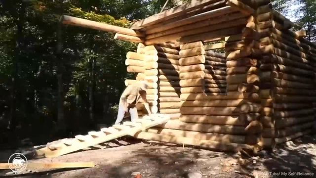 Man builds log cabin by hand