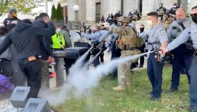 Graham police aiming pepper spray at the ground during the march to the polls.