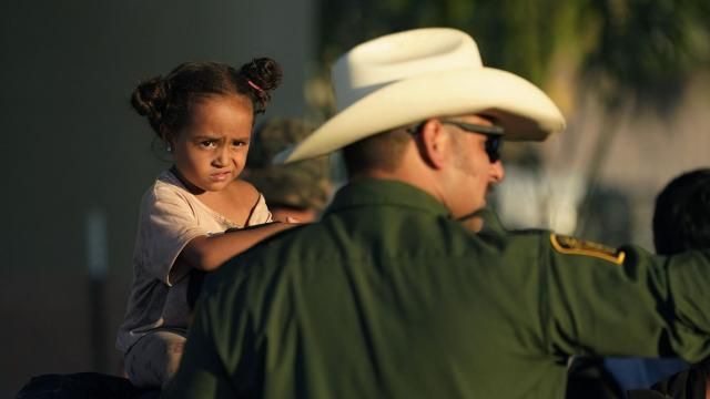 A young girl watches as she and other migrants who crossed the Rio Grande and entered the U.S. from Mexico are lined up for processing by U.S. Customs and Border Protection, Saturday, Sept. 23, 2023, in Eagle Pass, Texas. (AP Photo/Eric Gay)