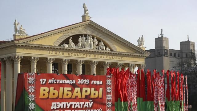 FILE - A woman walks past a huge election banner and Belarus national flags in Minsk, Belarus, on Nov. 13, 2019. Belarusians will cast ballots Sunday in tightly controlled parliamentary and local elections that are set to cement an authoritarian leader's rule, despite calls for a boycott by an opposition leader who described the balloting as a "senseless farce." (AP Photo, File) FILE - A woman walks past a huge election banner and Belarus national flags in Minsk, Belarus, on Nov. 13, 2019. Belarusians will cast ballots Sunday in tightly controlled parliamentary and local elections that are set to cement an authoritarian leader's rule, despite calls for a boycott by an opposition leader who described the balloting as a "senseless farce." (AP Photo, File)