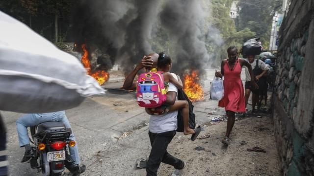 People walk past burning tires during a protest against Haitian Prime Minister Ariel Henry in Port-au-Prince, Haiti, Monday, Feb. 5, 2024. Banks, schools and government agencies closed in Haiti’s northern and southern regions on Monday while protesters blocked main routes with blazing tires and paralyzed public transportation, according to local media reports. (AP Photo/Odelyn Joseph) People walk past burning tires during a protest against Haitian Prime Minister Ariel Henry in Port-au-Prince, Haiti, Monday, Feb. 5, 2024. Banks, schools and government agencies closed in Haiti’s northern and southern regions on Monday while protesters blocked main routes with blazing tires and paralyzed public transportation, according to local media reports. (AP Photo/Odelyn Joseph)