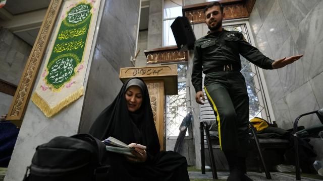 A woman fills out her ballot as a policeman walks past during the parliamentary and Assembly of Experts elections at a polling station in Tehran, Iran, Friday, March 1, 2024. Iran held the country's first election since the mass 2022 protests over mandatory hijab laws after the death in police custody of Mahsa Amini, with questions looming over just how many people will turn out at the polls. (AP Photo/Vahid Salemi) A woman fills out her ballot as a policeman walks past during the parliamentary and Assembly of Experts elections at a polling station in Tehran, Iran, Friday, March 1, 2024. Iran held the country's first election since the mass 2022 protests over mandatory hijab laws after the death in police custody of Mahsa Amini, with questions looming over just how many people will turn out at the polls. (AP Photo/Vahid Salemi)