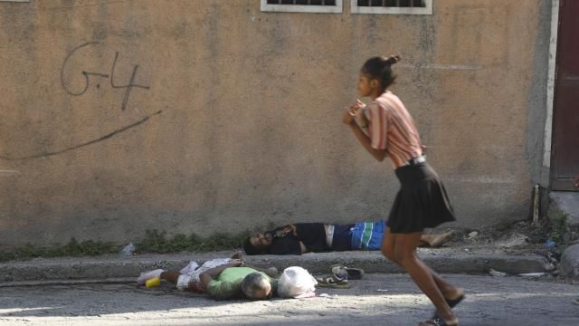 A woman walks past bodies of two men killed by unknown assailants in Port-au-Prince, Haiti, Sunday, March 3, 2024. Hundreds of inmates fled Haiti's main prison after armed gangs stormed the facility overnight. (AP Photo/Odelyn Joseph) A woman walks past bodies of two men killed by unknown assailants in Port-au-Prince, Haiti, Sunday, March 3, 2024. Hundreds of inmates fled Haiti's main prison after armed gangs stormed the facility overnight. (AP Photo/Odelyn Joseph)