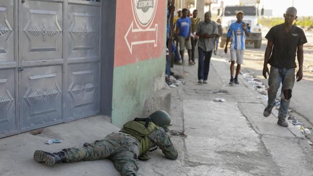 Pedestrians was past a soldier guarding the area of the international airport in Port-au-Prince, Haiti, Monday, March 4, 2024. Gang members exchanged gunfire with police and soldiers around the airport in the latest of a series of attacks on government sites, which includes a mass escape from the country's two biggest prisons. (AP Photo/Odelyn Joseph) Pedestrians was past a soldier guarding the area of the international airport in Port-au-Prince, Haiti, Monday, March 4, 2024. Gang members exchanged gunfire with police and soldiers around the airport in the latest of a series of attacks on government sites, which includes a mass escape from the country's two biggest prisons. (AP Photo/Odelyn Joseph)