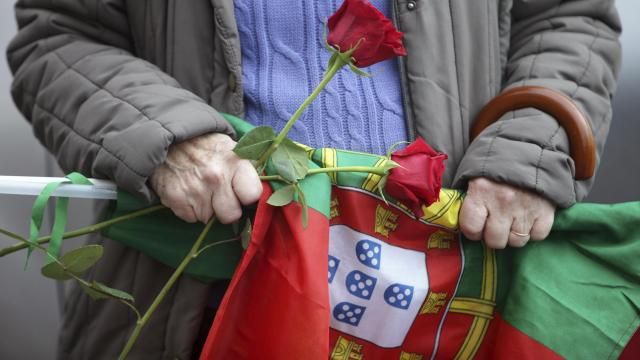 A Socialist Party supporter holds roses and a Portuguese flag during an election campaign action with their leader Pedro Nuno Santos on the street in the Lisbon suburb of Moscavide, Friday, March 8, 2024. Portugal is holding an early general election on Sunday when 10.8 million registered voters elect 230 lawmakers to the National Assembly, the country's Parliament. (AP Photo/Joao Henriques) A Socialist Party supporter holds roses and a Portuguese flag during an election campaign action with their leader Pedro Nuno Santos on the street in the Lisbon suburb of Moscavide, Friday, March 8, 2024. Portugal is holding an early general election on Sunday when 10.8 million registered voters elect 230 lawmakers to the National Assembly, the country's Parliament. (AP Photo/Joao Henriques)