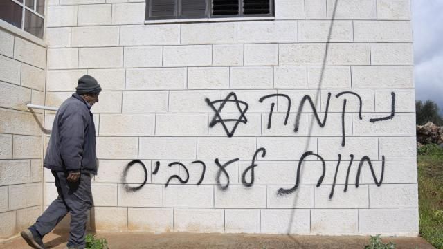 FILE - A man looks at graffiti that reads, in Hebrew, "revenge, death to Arabs," allegedly sprayed by Jewish West Bank settlers in the Palestinian West Bank village of Turmus Ayya, Feb. 18, 2024. The U.S. has imposed sanctions on a group of three extremist Israeli West Bank settlers who are accused of harassing and attacking Palestinians in an attempt to pressure them to leave their land. (AP Photo/Nasser Nasser, File) FILE - A man looks at graffiti that reads, in Hebrew, "revenge, death to Arabs," allegedly sprayed by Jewish West Bank settlers in the Palestinian West Bank village of Turmus Ayya, Feb. 18, 2024. The U.S. has imposed sanctions on a group of three extremist Israeli West Bank settlers who are accused of harassing and attacking Palestinians in an attempt to pressure them to leave their land. (AP Photo/Nasser Nasser, File)