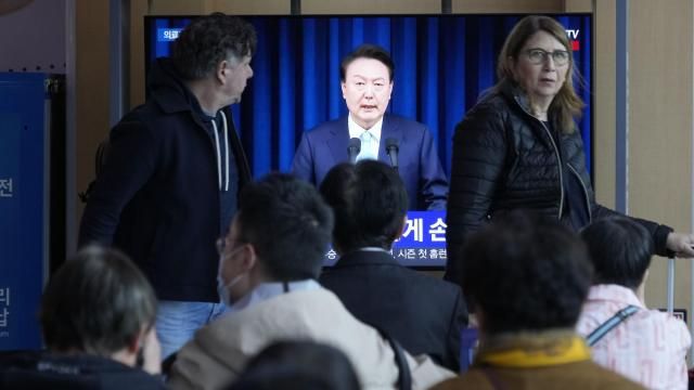 People watch a TV screen showing the live broadcast of South Korean President Yoon Suk Yeol’s addressing the nation at the Seoul Railway Station in Seoul, South Korea, Monday, April 1, 2024. President Yoon vowed Monday not to back down in the face of vehement protests by doctors seeking to spike his plan to drastically increase medical school admissions, as he called their walkouts “an illegal collective action” that poses "a grave threat to our society.” (AP Photo/Ahn Young-joon) People watch a TV screen showing the live broadcast of South Korean President Yoon Suk Yeol’s addressing the nation at the Seoul Railway Station in Seoul, South Korea, Monday, April 1, 2024. President Yoon vowed Monday not to back down in the face of vehement protests by doctors seeking to spike his plan to drastically increase medical school admissions, as he called their walkouts “an illegal collective action” that poses "a grave threat to our society.” (AP Photo/Ahn Young-joon)