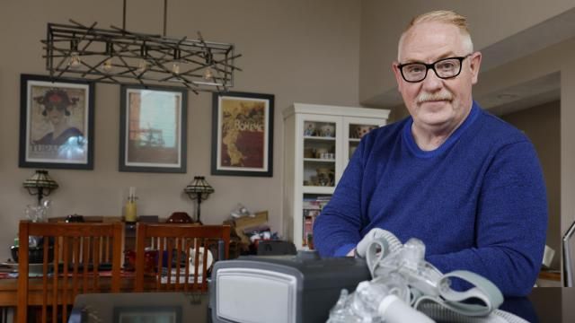FILE - Jeffrey Reed, who experienced persistent sinus infections and two bouts of pneumonia while using a Philips CPAP machine, poses with the device at his home, Oct. 20, 2022, in Marysville, Ohio. The company responsible for a global recall of sleep apnea machines will be barred from resuming production at U.S. facilities until it meets a number of safety requirements under a long-awaited settlement announced Tuesday, April 9, 2024 by federal officials. (AP Photo/Jay LaPrete, file) FILE - Jeffrey Reed, who experienced persistent sinus infections and two bouts of pneumonia while using a Philips CPAP machine, poses with the device at his home, Oct. 20, 2022, in Marysville, Ohio. The company responsible for a global recall of sleep apnea machines will be barred from resuming production at U.S. facilities until it meets a number of safety requirements under a long-awaited settlement announced Tuesday, April 9, 2024 by federal officials. (AP Photo/Jay LaPrete, file)