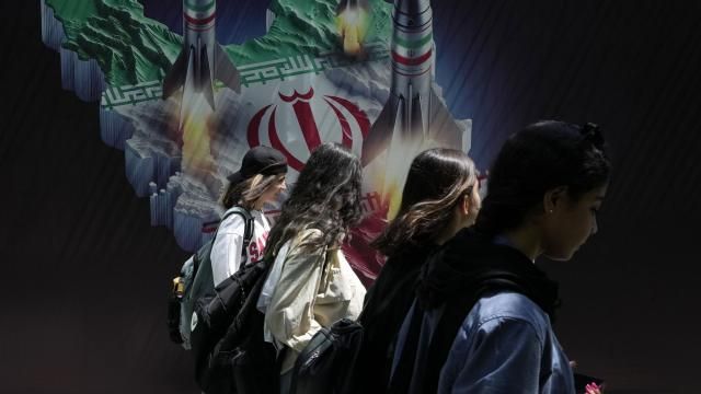 Iranian women without wearing their mandatory Islamic headscarf walk past a banner showing missiles being launched from Iranian map in northern Tehran, Iran, Friday, April 19, 2024. Iran fired air defenses at a major air base and a nuclear site near the central city of Isfahan after spotting drones early Friday morning, raising fears of a possible Israeli strike in retaliation for Tehran's unprecedented drone-and-missile assault on the country. (AP Photo/Vahid Salemi) Iranian women without wearing their mandatory Islamic headscarf walk past a banner showing missiles being launched from Iranian map in northern Tehran, Iran, Friday, April 19, 2024. Iran fired air defenses at a major air base and a nuclear site near the central city of Isfahan after spotting drones early Friday morning, raising fears of a possible Israeli strike in retaliation for Tehran's unprecedented drone-and-missile assault on the country. (AP Photo/Vahid Salemi)